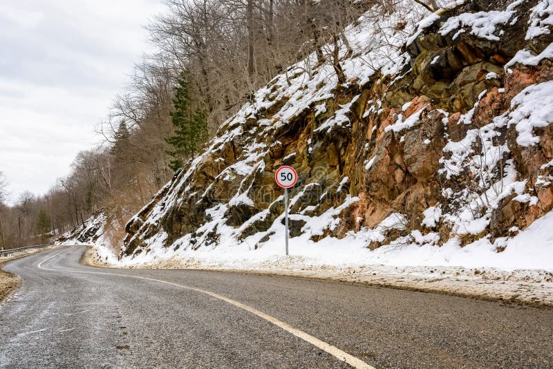 Speed limit road sign on winter mountain road