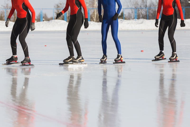 Speed skating competition on ice rink at winter sunny day - sportsmen ready for start