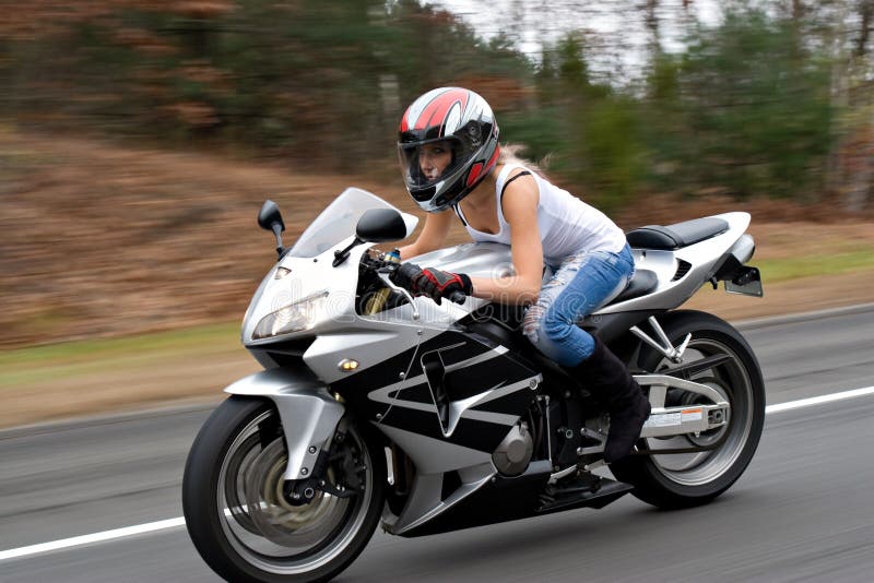 Žena jezdí na motocyklu na dálnici rychlostí s motion blur vidět v pozadí.