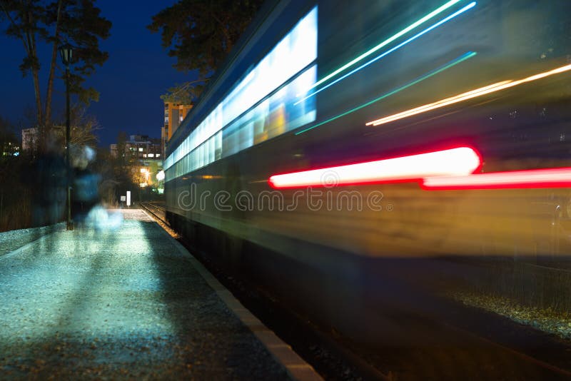 Speeding train leaving station with passengers at night. Night train stock images, royalty-free photos and pictures