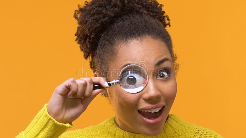 Speelse jonge vrouw die camera door vergrootglas, nieuwsgierigheidsonderzoek bekijken