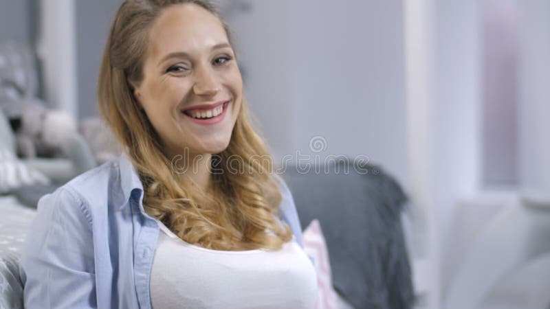 Speelse zwangere vrouw die bij camera glimlachen