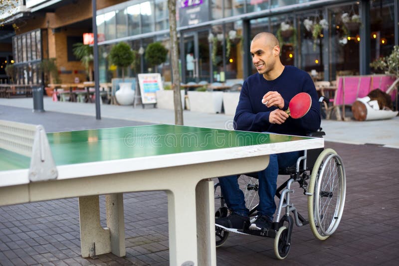 Disabled man enjoying a game of ping pong in his wheelchair. Disabled man enjoying a game of ping pong in his wheelchair