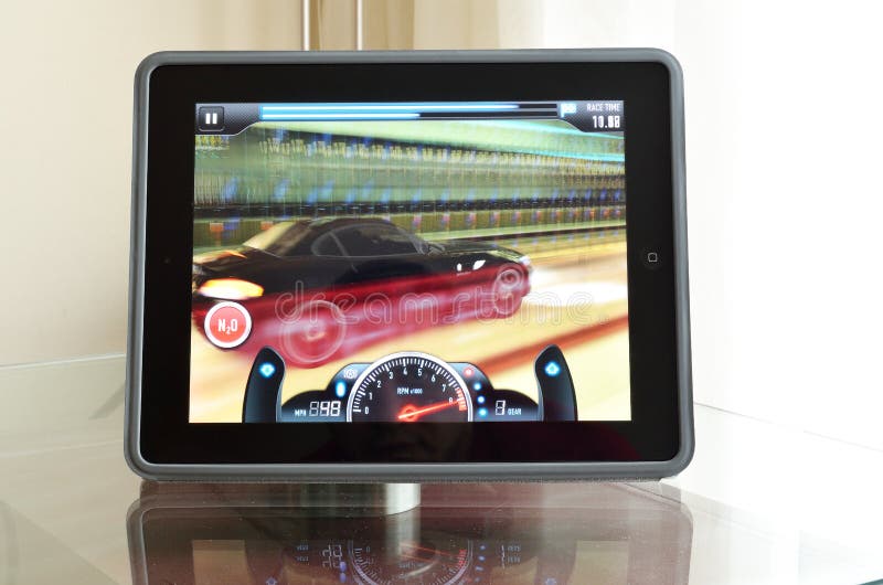 An Ipad 4 with retina display on the glass table with Need for speed game on the screen. An Ipad 4 with retina display on the glass table with Need for speed game on the screen