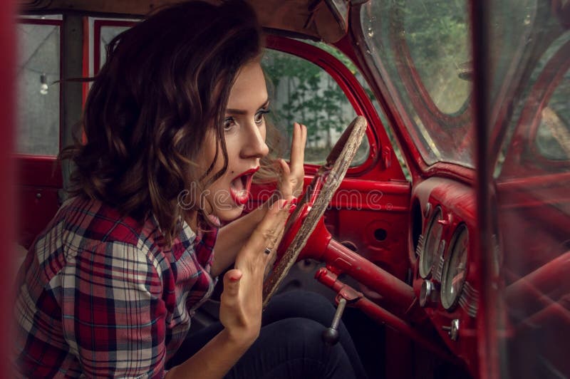 Speld-op meisje in een plaid wordt het overhemd bang gemaakt en het gillen, bekijkend de snelheidsmeter in de cabine van oud aang stock fotografie Speld-op meisje in een plaid wordt het overhemd bang gemaakt en het gillen, bekijkend de snelheidsmeter in de cabine van oud aang stock fotografie