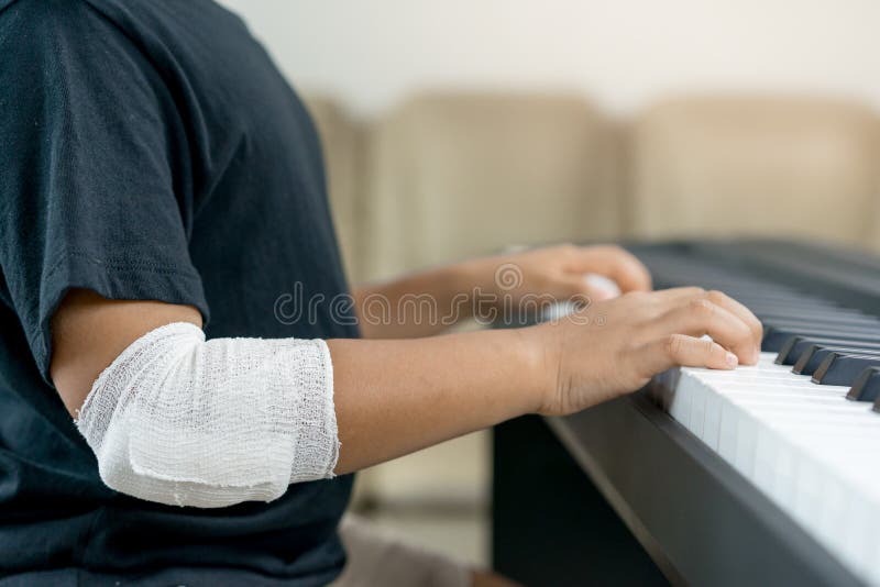 An Asian boys at the wounded hands are playing the piano. An Asian boys at the wounded hands are playing the piano