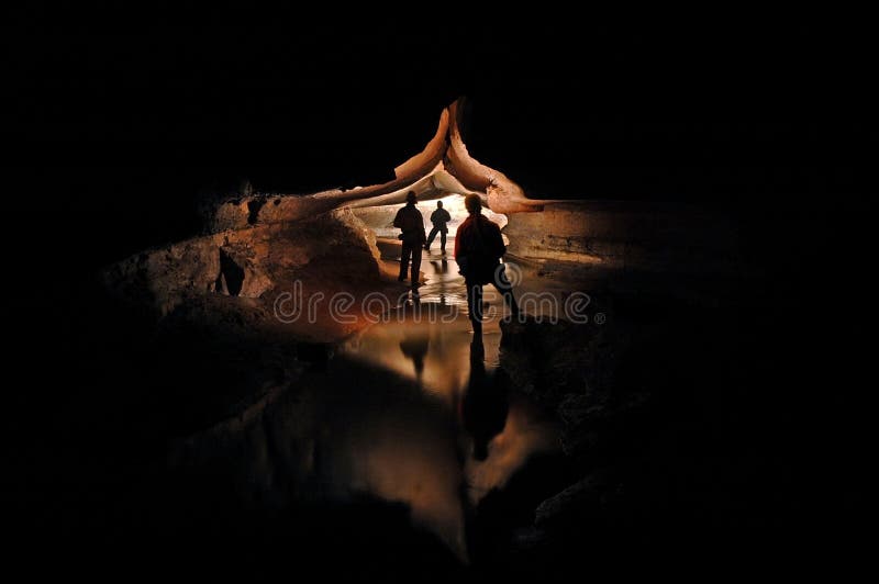 Spelunkers die een ondergrondse holrivier onderzoeken royalty-vrije stock afbeelding Spelunkers die een ondergrondse holrivier onderzoeken royalty-vrije stock afbeelding