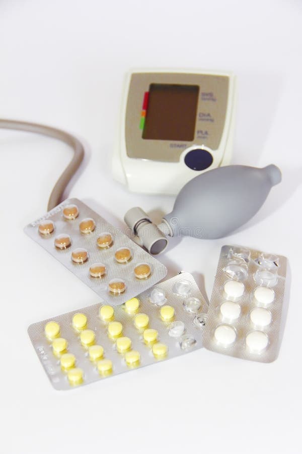 Sphygmomanometer medical tonometer and multi-colored pills on white background royalty free stock photo