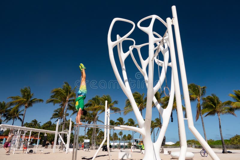 Spiaggia del sud, Florida condizione dell'uomo sulle sue mani sulle barre di paralleli fotografia stock libera da diritti Spiaggia del sud, Florida condizione dell'uomo sulle sue mani sulle barre di paralleli fotografia stock libera da diritti