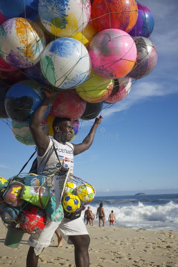 RIO DE JANEIRO, BRAZIL - JANUARY 19, 2014: Beach vendor selling colorful beach balls carries his merchandise along Ipanema Beach. RIO DE JANEIRO, BRAZIL - JANUARY 19, 2014: Beach vendor selling colorful beach balls carries his merchandise along Ipanema Beach.