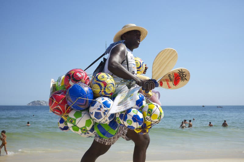 RIO DE JANEIRO, BRAZIL - FEBRUARY 20, 2014: Beach vendor selling colorful balls and toys carries his merchandise along Ipanema Beach. RIO DE JANEIRO, BRAZIL - FEBRUARY 20, 2014: Beach vendor selling colorful balls and toys carries his merchandise along Ipanema Beach.