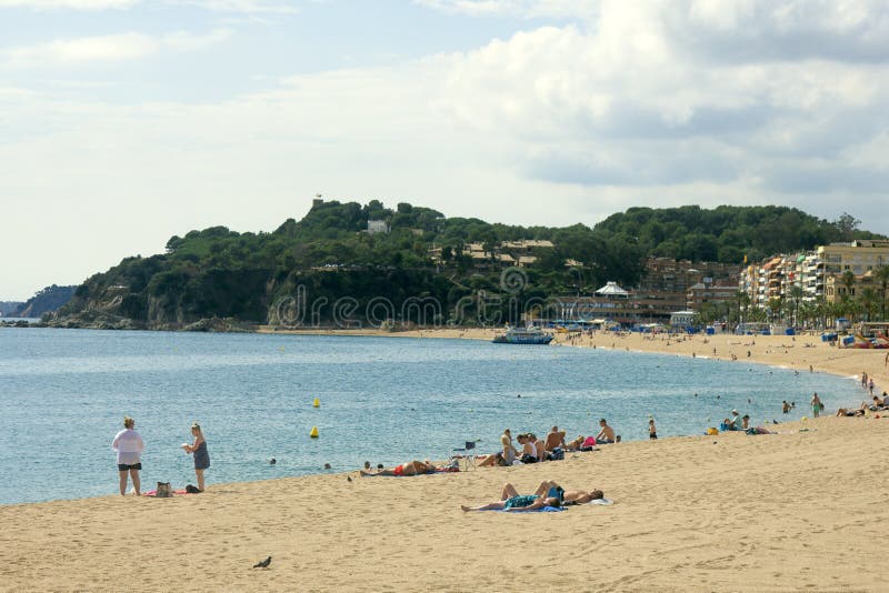 Spain, Lloret de Mar - October 2, 2017: tourist beach with palm trees hotels and vacationers in Mediterranean low season. Spain, Lloret de Mar - October 2, 2017: tourist beach with palm trees hotels and vacationers in Mediterranean low season