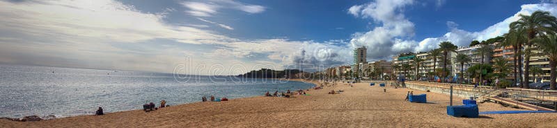 Spain, Lloret de Mar - October 2, 2017: tourist beach with palm trees hotels and vacationers in Mediterranean low season. Spain, Lloret de Mar - October 2, 2017: tourist beach with palm trees hotels and vacationers in Mediterranean low season