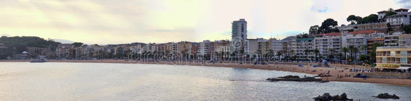 Spain, Lloret de Mar - October 2, 2017: tourist beach with palm trees hotels and vacationers in Mediterranean low season. Spain, Lloret de Mar - October 2, 2017: tourist beach with palm trees hotels and vacationers in Mediterranean low season