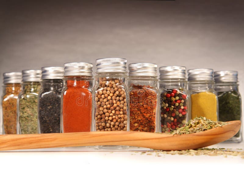 Spices in bottles with wooden spoon