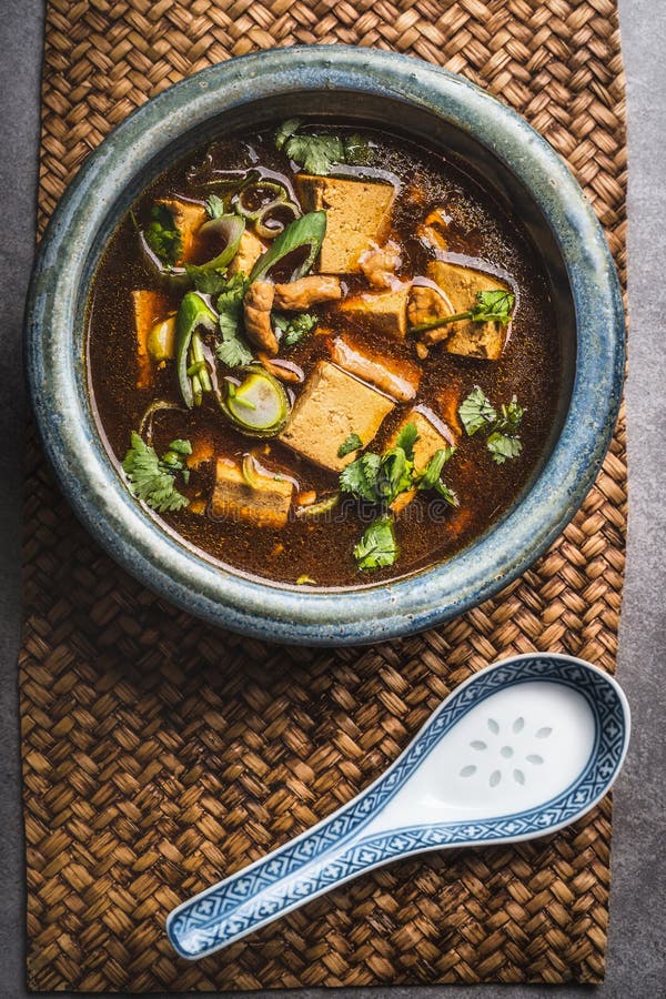 Spicy asian soup with tofu and meat in bowl , top view. Sichuan soup.