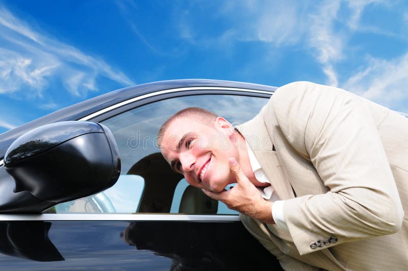 Vain business man checking his looks in the mirror of his car, with blue sky background. Vain business man checking his looks in the mirror of his car, with blue sky background