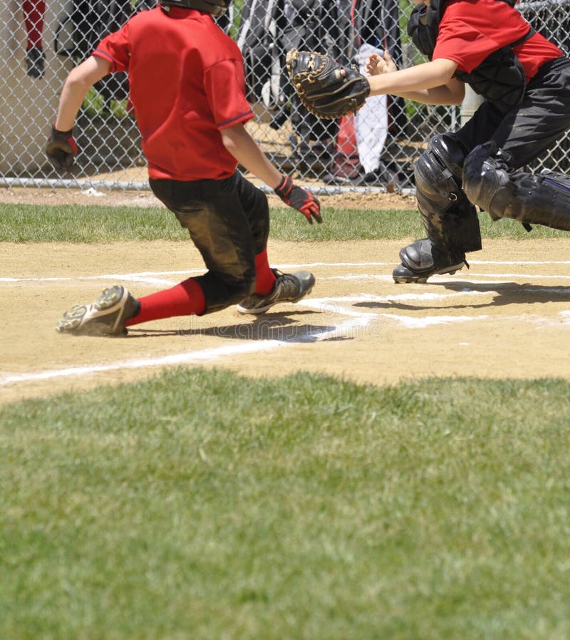 Little league ball player sliding into home plate and the catcher is ready to make the tag. Little league ball player sliding into home plate and the catcher is ready to make the tag.