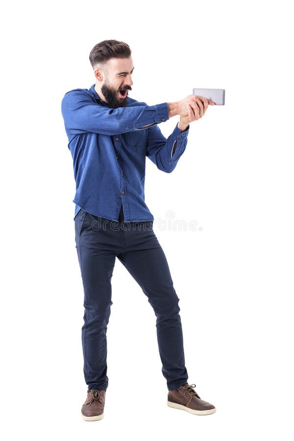 Spielerischer Geschäftsmann, der Handy als Pistole zielt als Actionfilmheld hält lizenzfreie stockfotos Spielerischer Geschäftsmann, der Handy als Pistole zielt als Actionfilmheld hält lizenzfreie stockfotos