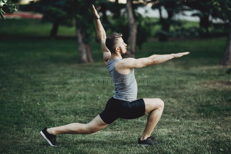 Spier geschikte mens die yoga in ochtendpark doen stock foto's Spier geschikte mens die yoga in ochtendpark doen stock foto's