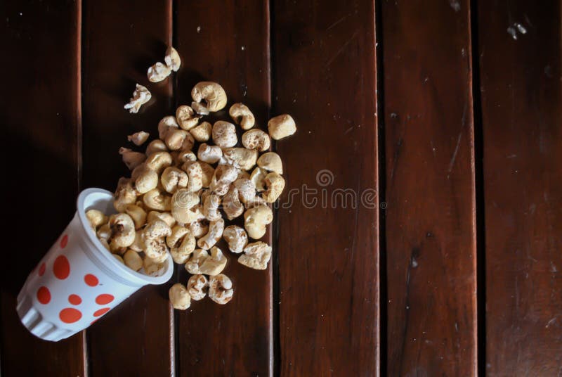 Spilled Popcorn from the Red Spot Bucket on Wooden Table Stock Photo