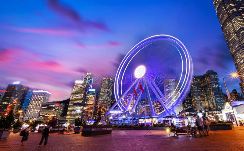 Spinning Ferris Wheel in Motion at Central Pier in Hong Kong During Sunset Blue Hour With Moving Clouds