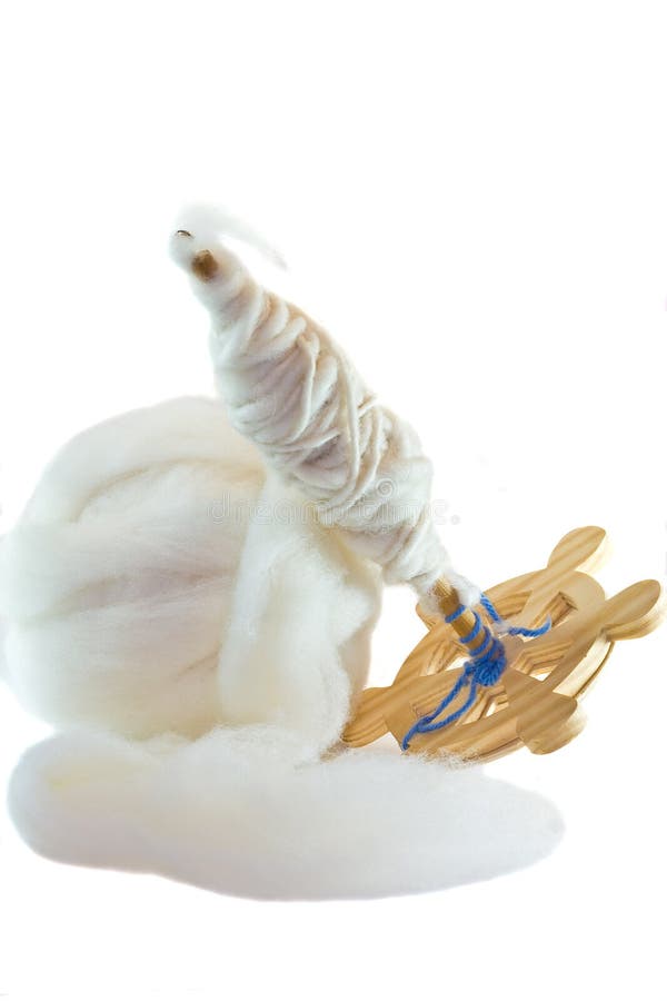 A vertical picture of a ball of roving fiber next to a drop spindle that has the same fiber spun into yarn on it on an isolated white background. A vertical picture of a ball of roving fiber next to a drop spindle that has the same fiber spun into yarn on it on an isolated white background.