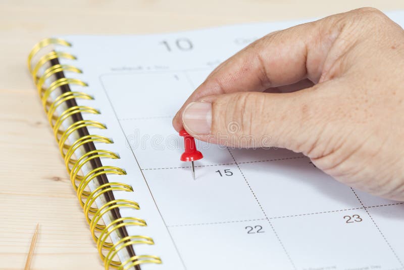Spinta della mano un segno del perno sul calendario fotografie stock Spinta della mano un segno del perno sul calendario fotografie stock