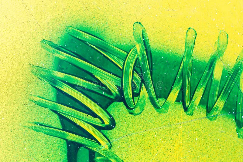 Spiral lines of green paint curves on yellow plastic surface. Abstract birght grunge background