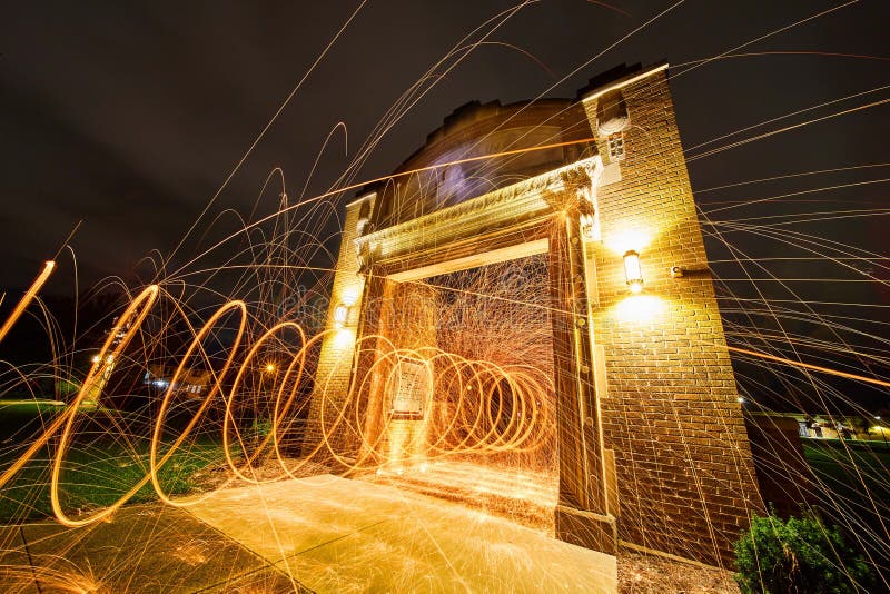 Spiral of Steel Wool Lights through Brick Archway at Night Stock Image