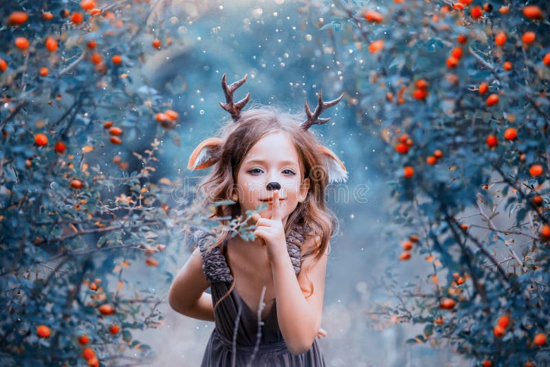 Spirit of the forest in the form of a child in a light brown dress, a baby deer playfully leads into the forest, the stock photos Spirit of the forest in the form of a child in a light brown dress, a baby deer playfully leads into the forest, the stock photos