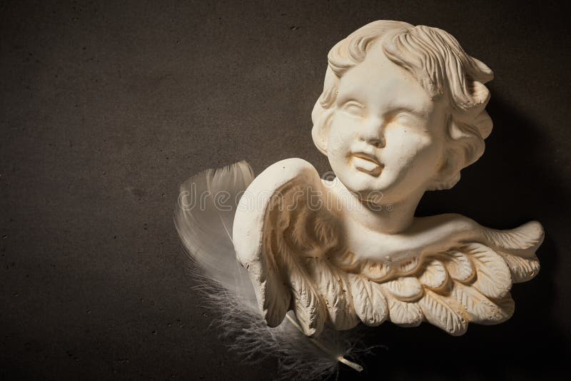 Memorial concept of angel figurine with feather stock photo Memorial concept of angel figurine with feather stock photo
