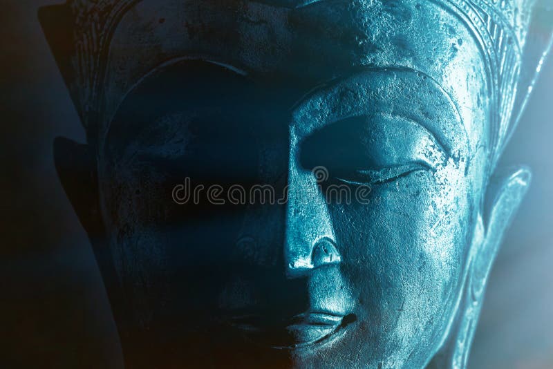 Spiritual enlightenment. Mindful Buddha face close-up with ethereal blue light. Mysticism and spirituality portrayed in calm close up image of peaceful buddhist meditation. Serene divine devotion. Spiritual enlightenment. Mindful Buddha face close-up with ethereal blue light. Mysticism and spirituality portrayed in calm close up image of peaceful buddhist meditation. Serene divine devotion