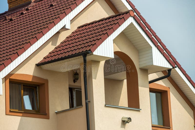 Spitzendetailfront des großen modernen teuren Wohnfamilienhäuschens mit geschichtetem braunem Dach, Ziegelsteinkamin, Stuckwände lizenzfreie stockfotografie Spitzendetailfront des großen modernen teuren Wohnfamilienhäuschens mit geschichtetem braunem Dach, Ziegelsteinkamin, Stuckwände lizenzfreie stockfotografie