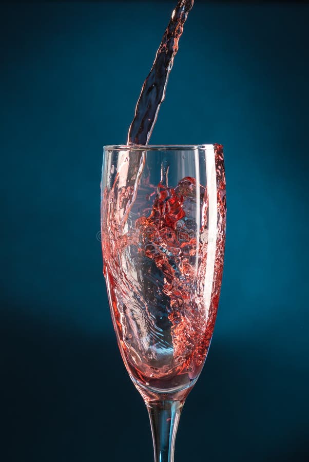 Splash in a Champagne Glass from Falling Red Wine on a Dark Blue