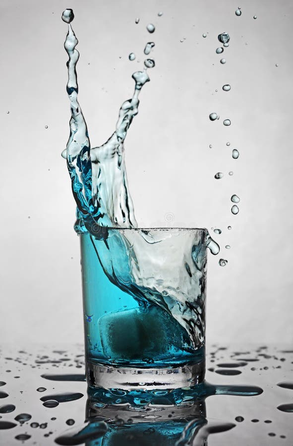 Splash in Glass of Blue Alcoholic Cocktail Drink with Ice Cube Stock