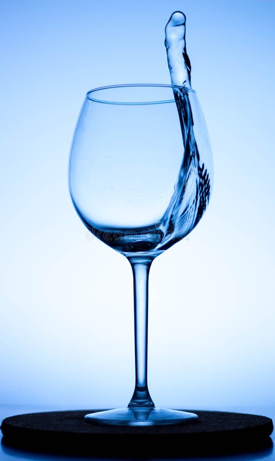 A Splash of Liquid in a Glass Wine Glass. Water Pouring Inside a Glass