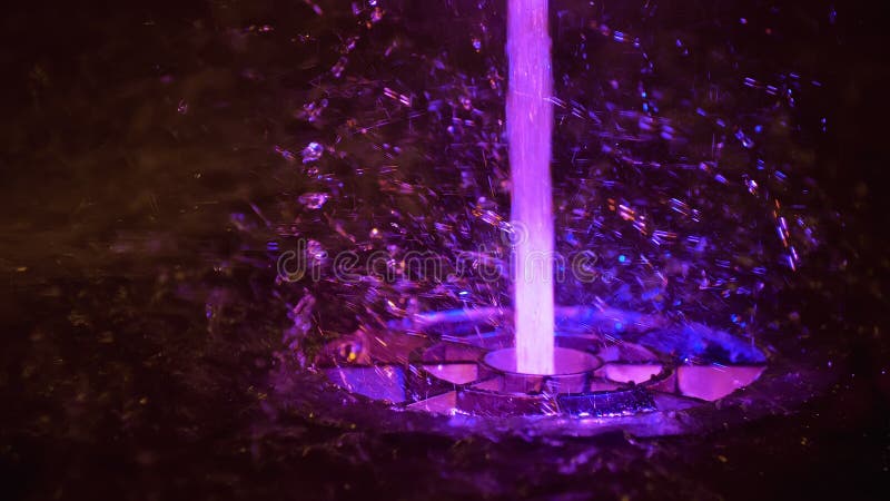 Splashes Of Colorful Fountain. Water Illuminated In Diverse Colors Falling On A Fountain Which Change Its Water Color In