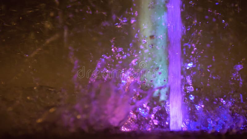 Splashes of colorful fountain. Water illuminated in diverse colors falling on a fountain which change its water color in. Dark, girl.