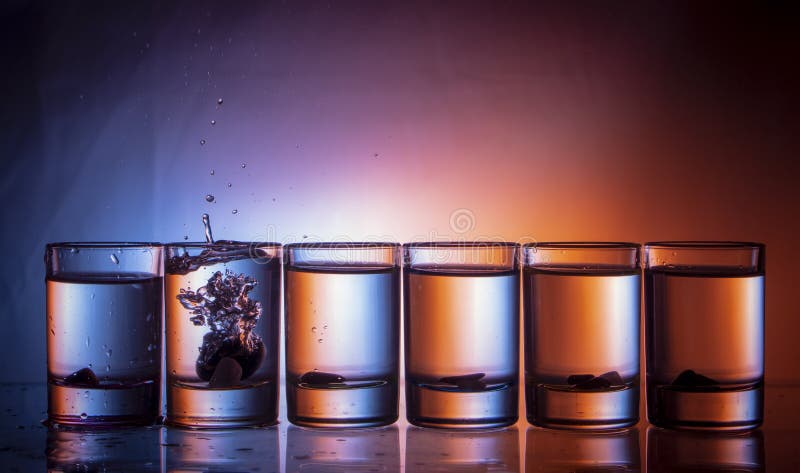 splashing fluid in a glass. That row of glasses on a blue-red background Close up