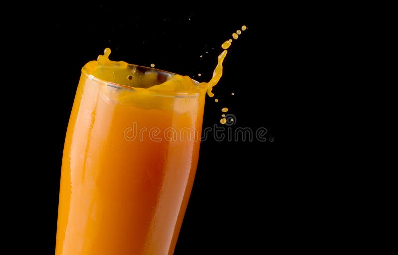 Orange juice splashing out of glass in front of black background. Orange juice splashing out of glass in front of black background.