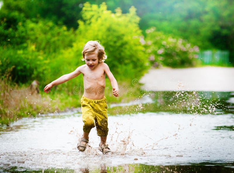 Little boy runs through a puddle. summer outdoor. Little boy runs through a puddle. summer outdoor