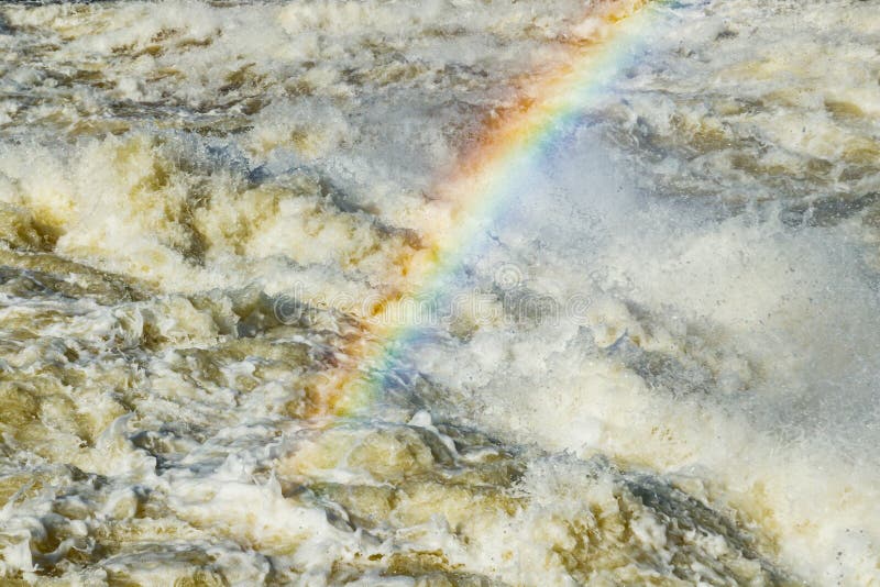 Splashing water waves with rainbow on the fast river stock image