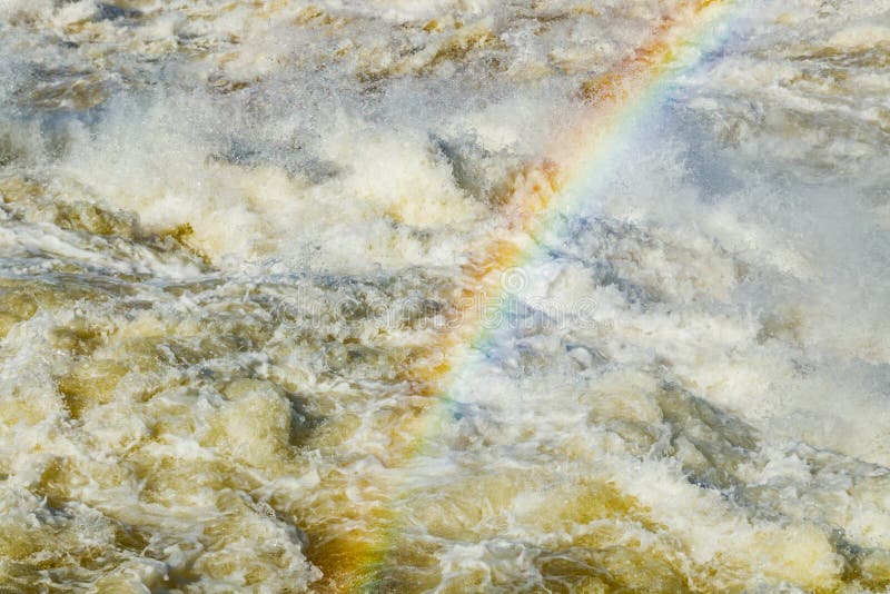 Splashing water waves with rainbow on the fast river royalty free stock photography