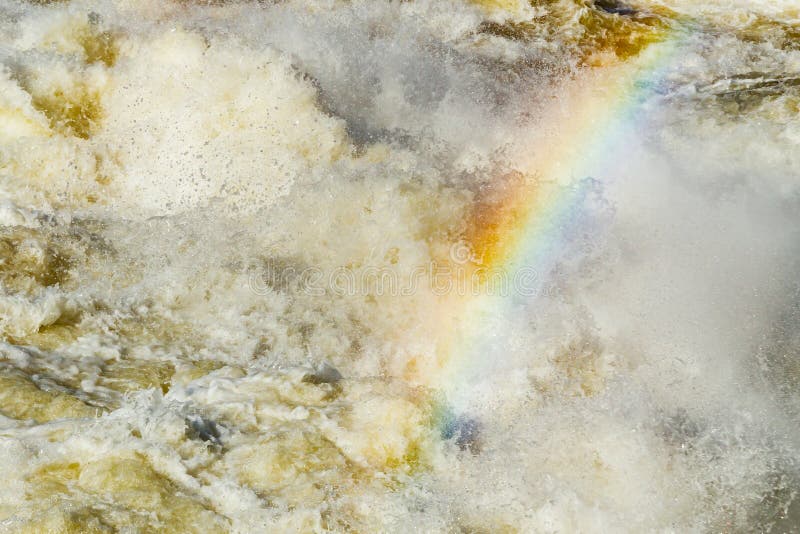 Splashing water waves with rainbow on the fast river stock image