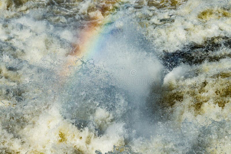Splashing water waves with rainbow on the fast river royalty free stock photo