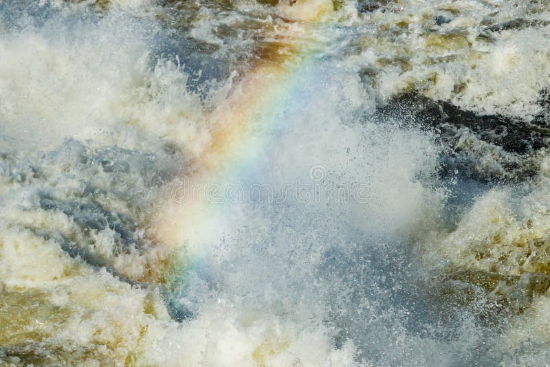 Splashing water waves with rainbow on the fast river royalty free stock photography