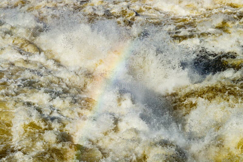 Splashing water waves with rainbow on the fast river royalty free stock image