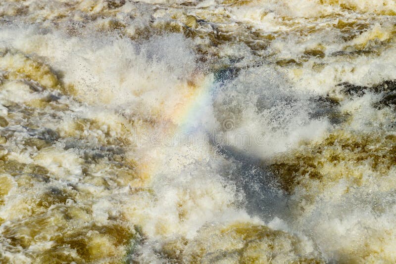Splashing water waves with rainbow on the fast river stock image