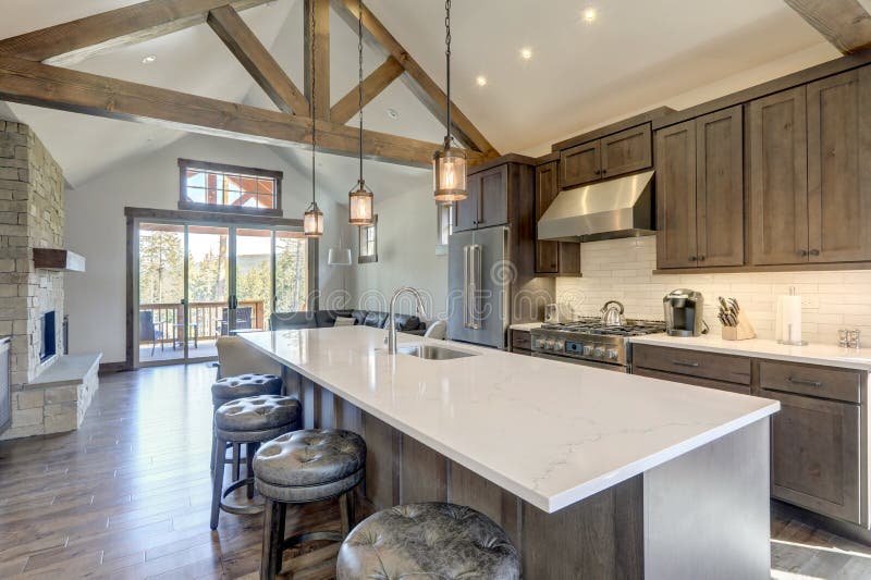 Amazing modern and rustic luxury kitchen with vaulted ceiling and wooden beams, long island with white quarts countertop and dark wood cabinets. Amazing modern and rustic luxury kitchen with vaulted ceiling and wooden beams, long island with white quarts countertop and dark wood cabinets